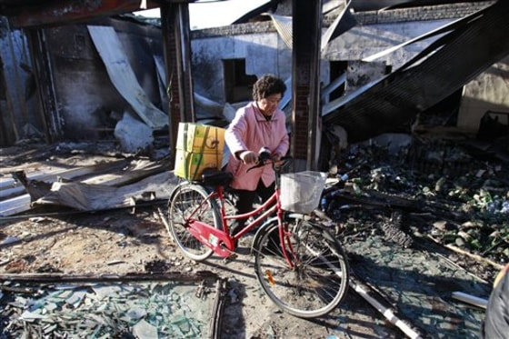 A woman walks amid destroyed houses on Yeonpyeong Island, South Korea, on Thursday.